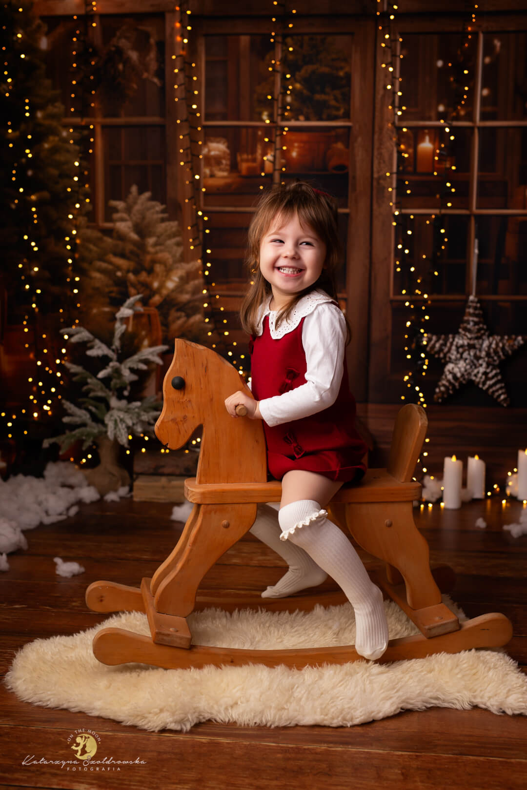 Kraków sesja świąteczan dziewczynki. Dziewczynka siedzi na bujamym konuku w świątecznej szklarni. Sesja wykonana w studio w Krakowie w 2025