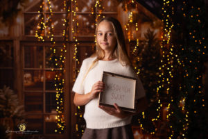 mini sesja świateczna kraków. Sesja świateczna dziewczynki trzymającej tabliczkę Wesołych świat