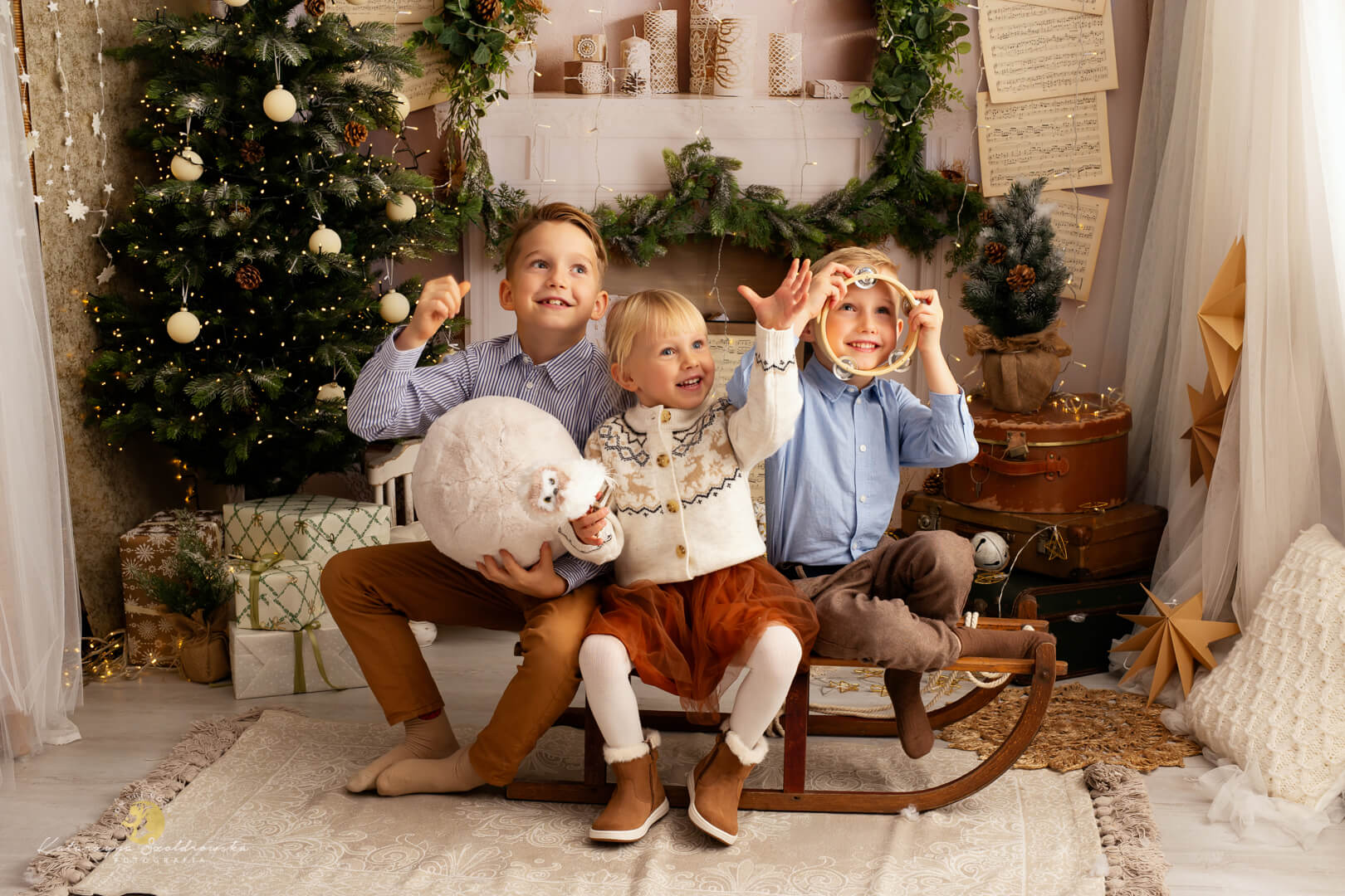 sesja świąteczna Kraków. Zdjecie trójki rodzeństwa na sankach. Sesja świąteczna w studio w Krakowie