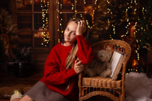 sesja świateczna kraków.Sesja świąteczna 2025 w studio w Krakowie,. Na zdjecie dziewczynka w czerwonym sweterku na brązowej scence.