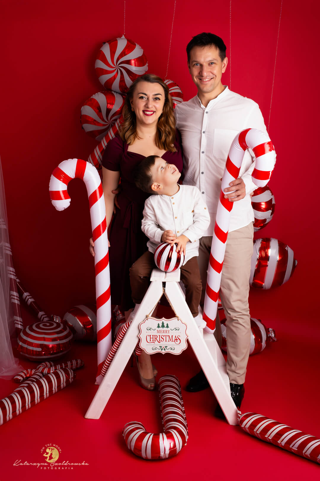 sesje świąr=teczne kraków. Rodzinna sesja świąteczna w studio w Krakowie na czerwonej nowoczesnej scence z balonami w kształcie cukierków